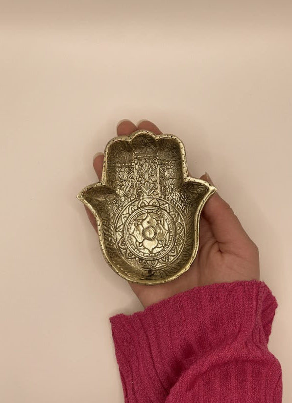 Messing-Schale in Form einer schützenden Hand mit Ornamentmuster, liegend in einer Hand vor warm beigefarbenem Hintergrund.